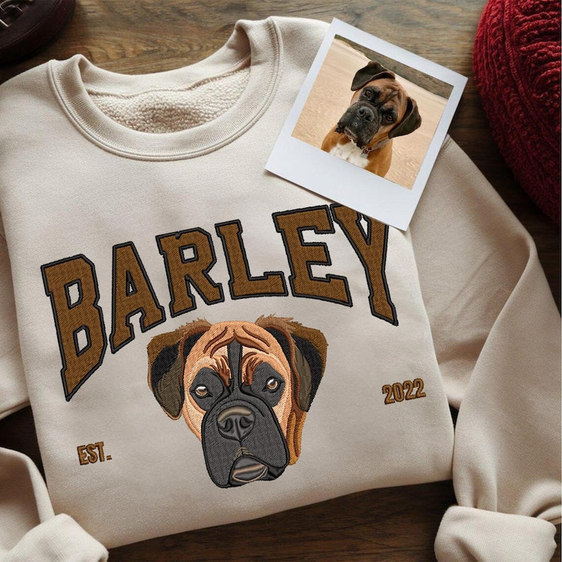 Felpa beige personalizzata con ricamo del ritratto di un cane e il nome “Barley”, affiancata da una foto stampata dello stesso cane.
